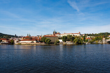 Fototapeta na wymiar Scenic view of Moldova River with skyline of City of Prague with St. Vitus Cathedral and castle the background on a sunny autumn day. Photo taken October 11th, 2023, Prague, Czech Republic.