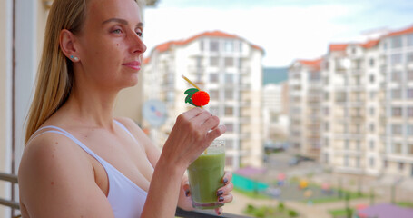 A woman drinking a delicious green smoothie on the terrace at home