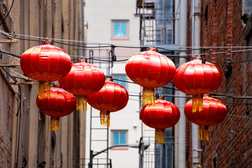Traditional red chinese lanterns hanging on cables above a city road in Chinatown in downtown San...