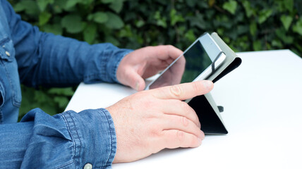 close-up hands of a man using his tablet on the table in the garden at home on daytime