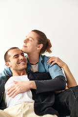 Two men sitting intertwined on top of each other in a loving embrace.