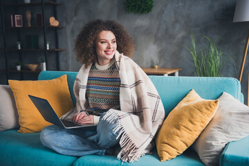 Photo of charming lovely dreamy woman sitting on soft sofa in cosy apartment indoors holding netbook