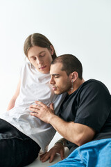 Fototapeta premium A man sits beside his boyfriend on a bed, sharing a moment of closeness.