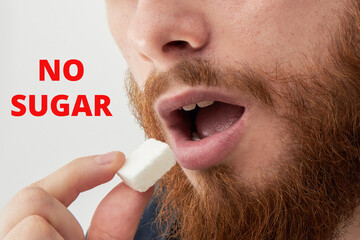 Young man with beard eating sugar cube with no sugar sign