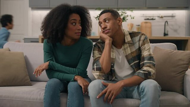 African American ethnic family sad parents father suffering headache pensive mother tired from misbehaving mischievous little boy difficult child active kid running apartment inside. Parenting problem