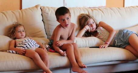 Children seated at sofa watching movie screen at home