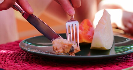 Closeup of hands holding fork and knife eating dessert sweet