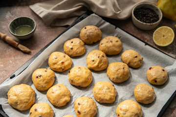 Homemade chocolate and lemon brioche buns rising on baking tray .