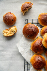 Freshly baked aromatic homemade chocolate and lemon brioche buns on cooling rack on linen tablecloth.