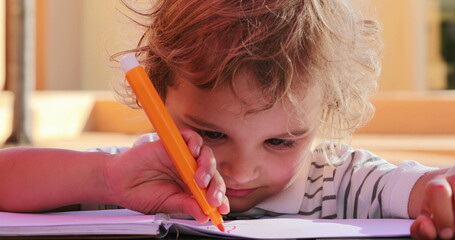 Child holding color pen and drawing outside concentrated and focused