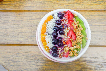 Healthy and colorful Breakfast Acai smoothie bowl with blueberries,kiwi fruit,chia seeds and coconut flakes on wooden background,close-up, top view, space for text.