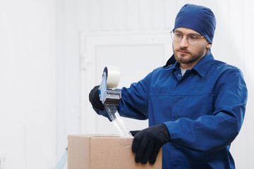 Warehouse industry, Packer working packs goods into box and seals them with tape on workplace