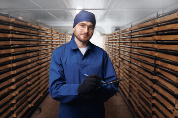 Industrial worker young man holding clipboard in drying chamber or growing mushrooms on farm