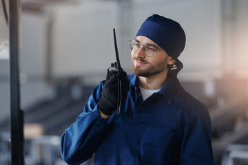Happy young man worker foreman talking on walkie talkie on warehouse, concept communication of...