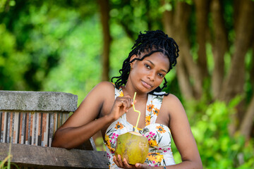 A young african lady drink coconut water at a park