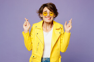 Young woman wears yellow shirt white t-shirt casual clothes glasses wait for special moment, keep fingers crossed, make wish, eyes closed isolated on plain light purple background. Lifestyle concept - obrazy, fototapety, plakaty