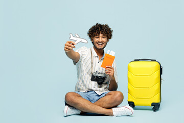 Traveler Indian man wears white casual clothes sit hold passport ticket plane mockup bag isolated...