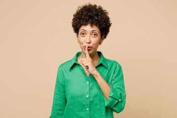 Young woman of African American ethnicity wear green shirt casual clothes say hush be quiet with...
