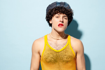 Young cool gay Latin man wear mesh tank top hat clothes with red lipstick make up biting lip...