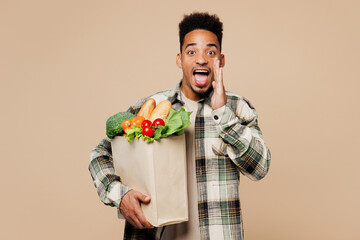 Young man wear grey shirt hold paper bag for takeaway mock up with food products scream sharing hot...