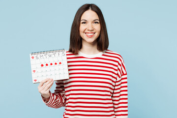Young smiling cheerful happy woman wear red casual clothes hold female periods pms calendar checking menstruation days looking camera isolated on plain blue background. Medical gynecological concept.