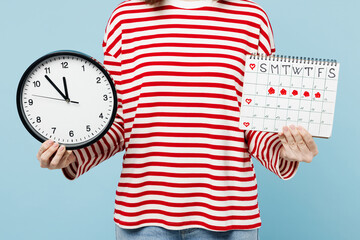 Close up cropped young happy woman she wear red casual clothes show clock hold female periods pms calendar checking menstruation days isolated on plain blue background. Medical gynecological concept.