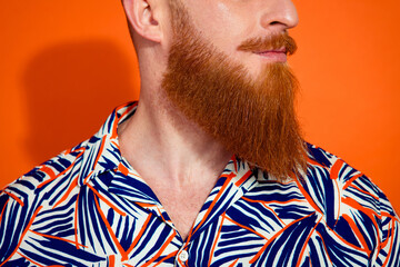 Cropped photo of positive good mood guy dressed print shirt looking emtpy space isolated orange color background