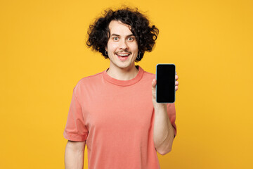 Young smiling happy man he wears pink t-shirt casual clothes hold in hand use mobile cell phone...