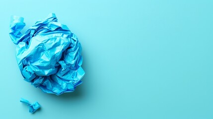   A crumpled blue paper next to scissors on a light blue backdrop Text space available