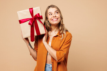 Young smiling Caucasian woman she wear orange shirt casual clothes hold present box with gift...