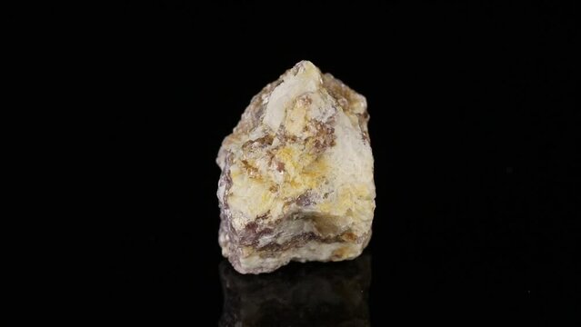 Polished mineral stone lepidolite rotates in a circle on a black background