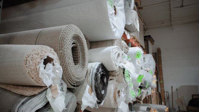 Piles of new rolls of carpet in a store warehouse. Carpet rolls stacked at store