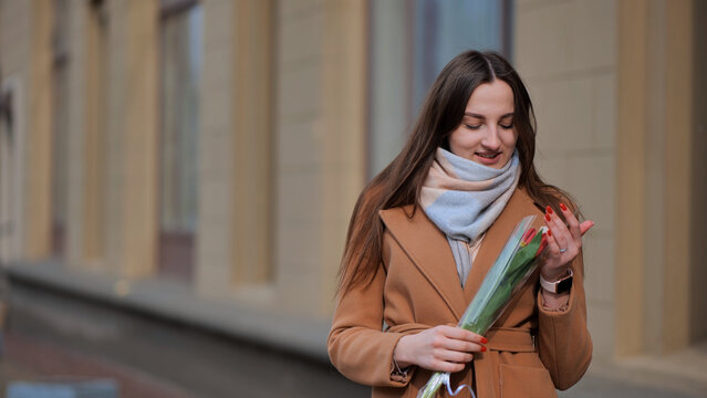 Portrait of a happy shade girl with a tulip in the background of the city in the cold season.