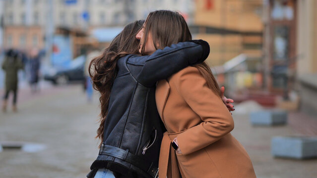 Two best friends meet on the streets of the city and hug.