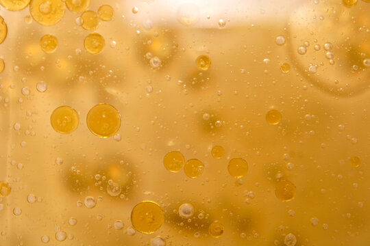 Golden circular oil bubbles floating on a clear water background.