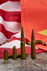 Group of bullets of various calibers lined up with the American and Chinese flags in the background.