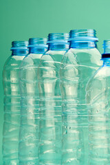 plastic bottles are organized in a row on a vivid green base, highlighting the necessity of waste reduction and recycling efforts.