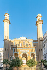 Ibn badis mosque in Abane Ramdane street near Martyr's square of algiers city. Facade entry panel with arabic calligraphy says "el imam sheikh abdelhamid ben badis". Clear blue sky and sunny day.