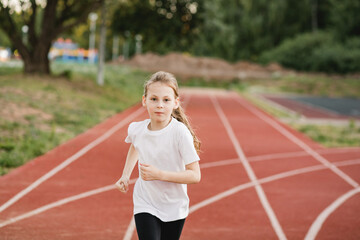 Focused child girl runner on a racing track. Confidence, empowerment, teamwork, accomplishment, and...