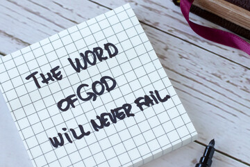 The Word of God will never fail, handwritten quote with holy bible on wood. Close-up. Inspiring Christian message about Jesus Christ's faithful promise, purpose, and plan. Biblical concept.