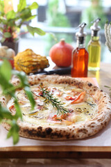 Crispy Italian pizza with cheese, smoked salmon, onion, rosemary, on a wooden cutting board, top view, selective focus.