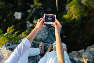 Man and woman laying on rock holding up picture