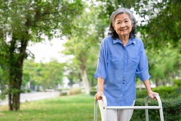 smiling senior woman walking with walker in park,concept of health insurance in elderly