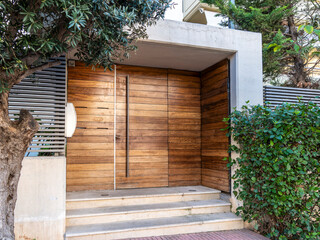 A contemporary design house entrance with a wooden door and steps by the sidewalk. Travel to Athens, Greece.