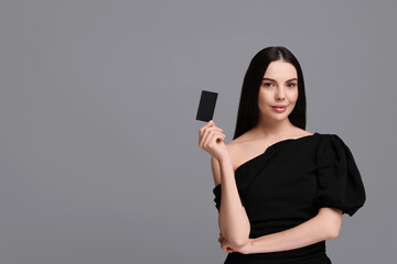 Naklejka premium Woman holding blank business card on grey background. Space for text