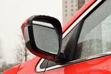 a side mirror of a modern car in raindrops