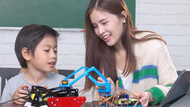 Asian teacher With school kids playing with a small robotic machine In Science Lesson.