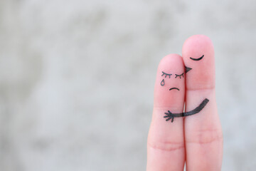 Finger art of displeased couple. Woman cries, man reassures her. He kisses and hugs her.