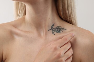 Woman with cool tattoo on light background, closeup