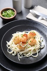 Delicious scallop pasta with green onion served on grey table